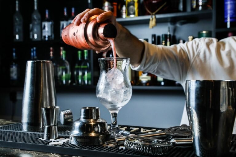 man-pouring-cocktail-from-shaker-in-the-glass-with-ice-bar-side-view.jpg